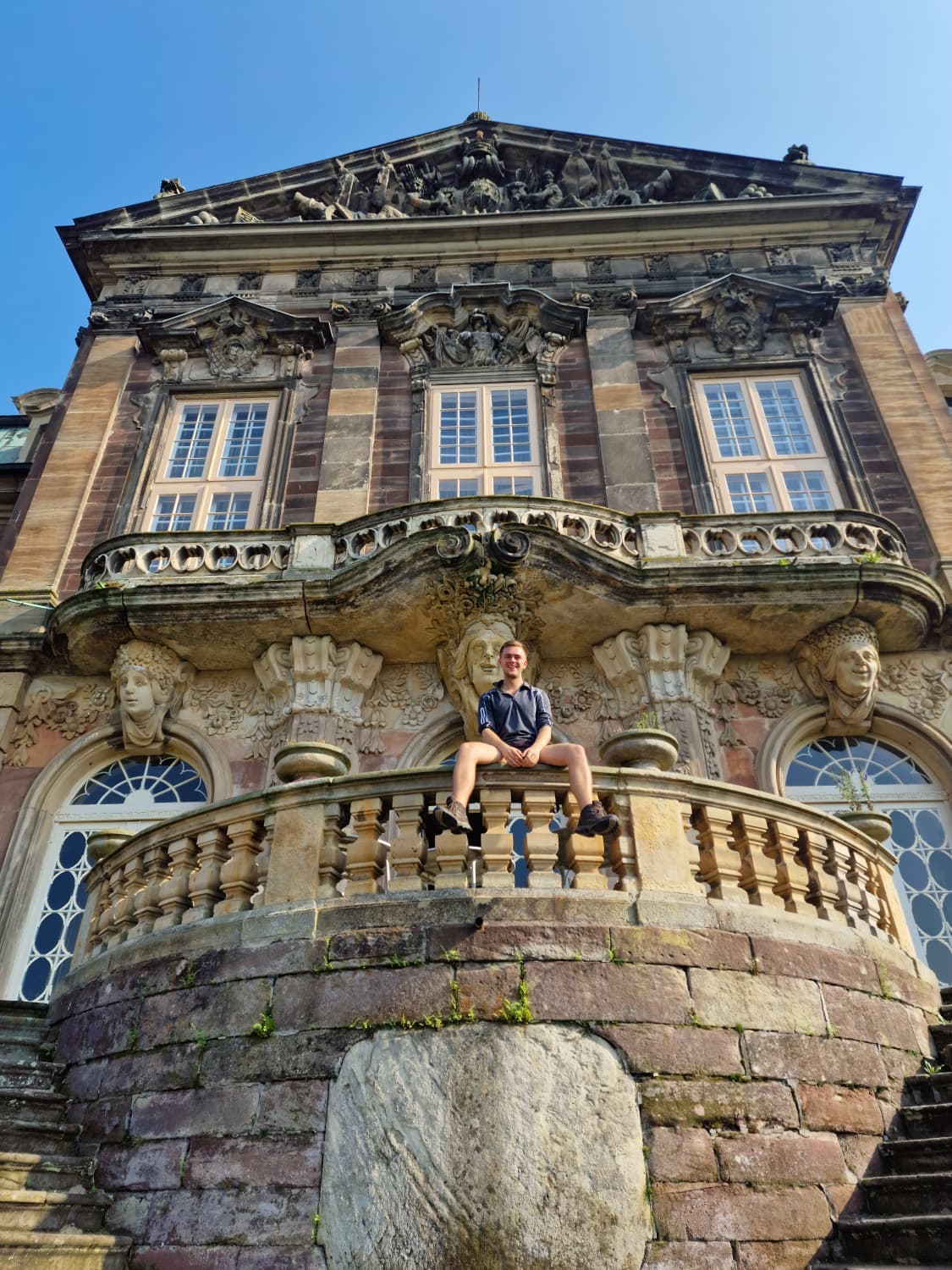 Erik sitting on a historic building balcony
